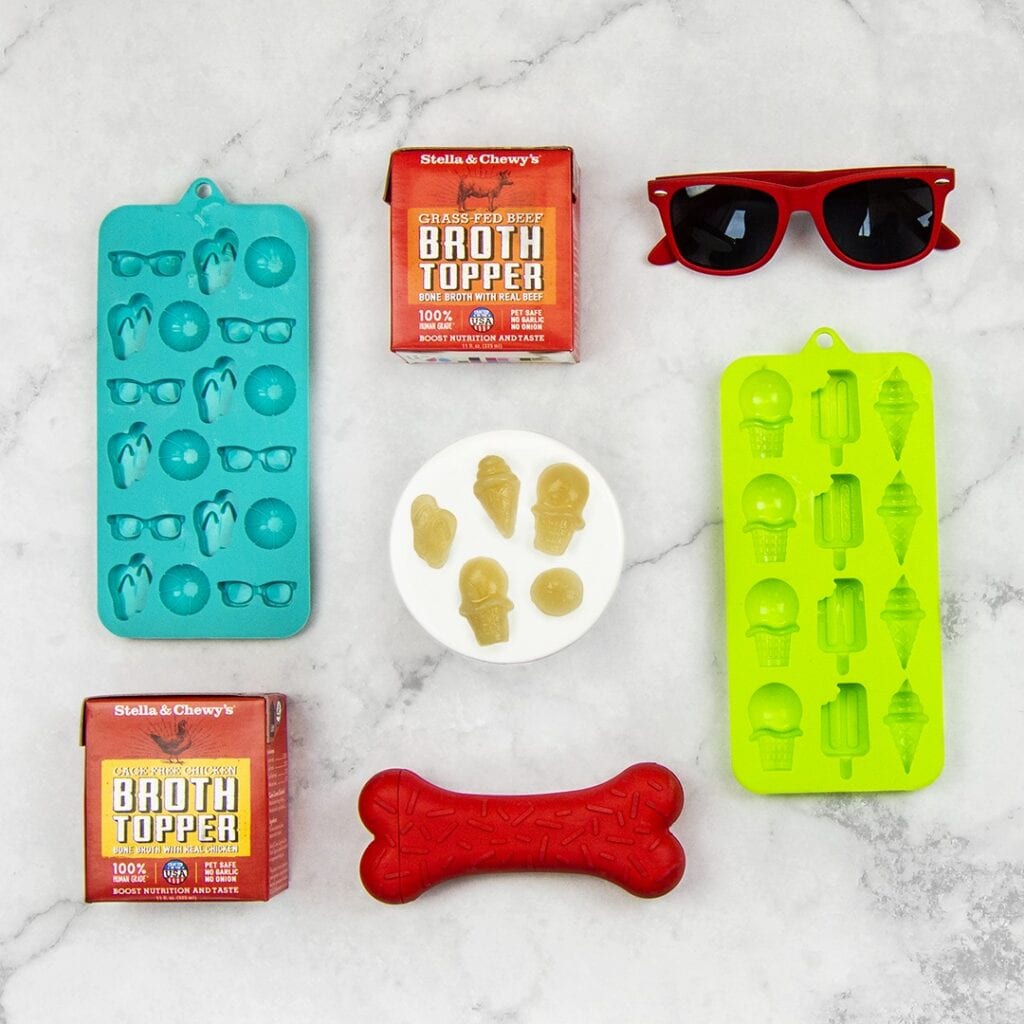 silicone molds for making frozen dog treats alongside broth toppers and a pair of sunglasses